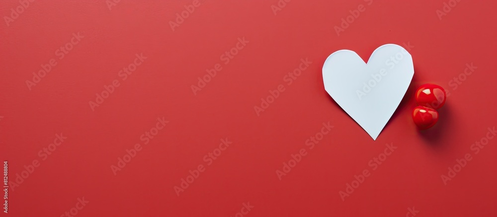 A greeting card concept showcasing a heart shaped paper pin on a piece of red note paper emphasizing the idea of note paper The image offers copy space A greeting card concept showcasing a heart shaped paper pin on a piece of red note paper emphasizing the idea of note paper The image offers copy space