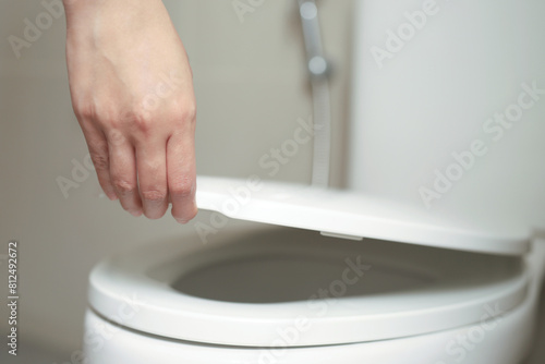 close up hand of a woman closing the lid of a toilet seat. Hygiene and health care concept.