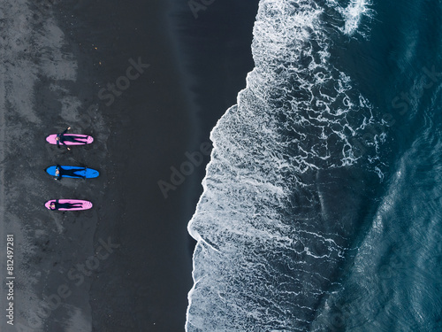 Group of friends surfers in wetsuit going to Extreme winter surfing in North ocean, aerial top view. Friendship adventure travel sport concept