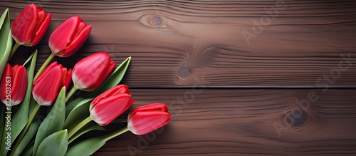 In a spring park a grouping of red tulips is arranged over a wooden table forming a valentine s day background The top view of this scene offers a copy space image