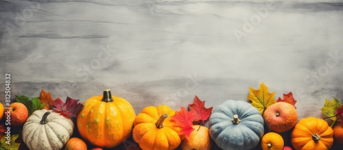 A retro toned scene with a harvest of pumpkins colorful fall leaves and gray stone with copy space image in a flat lay style