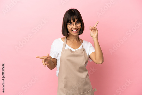 Restaurant waiter over isolated pink background pointing finger to the laterals and happy photo