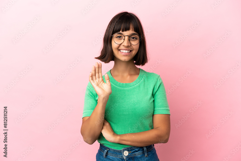 Young mixed race woman isolated on pink background saluting with hand with happy expression Young mixed race woman isolated on pink background saluting with hand with happy expression