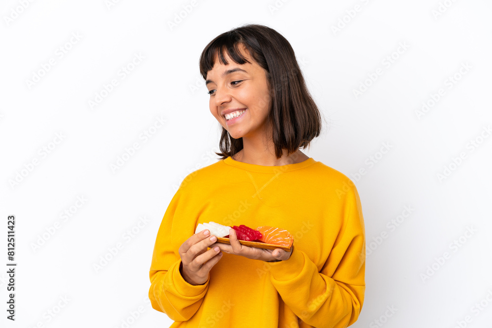Young mixed race woman holding sashimi isolated on white background looking to the side and smiling Young mixed race woman holding sashimi isolated on white background looking to the side and smiling