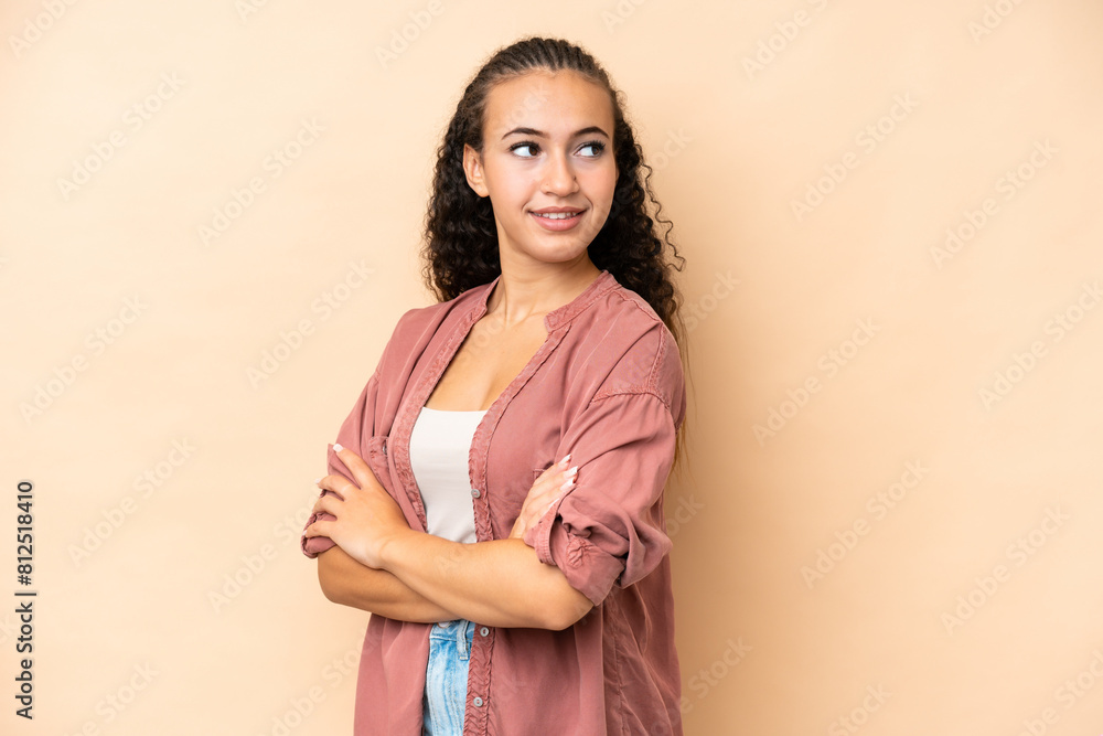 Obraz premium Young woman isolated on beige background looking to the side