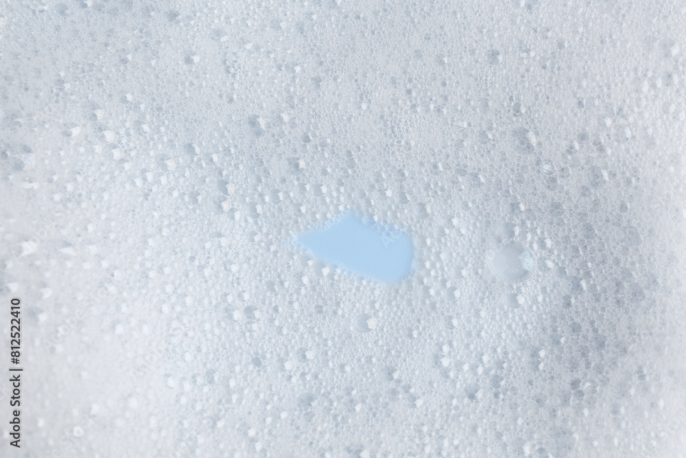 Fototapeta premium White fluffy foam on light blue background, top view