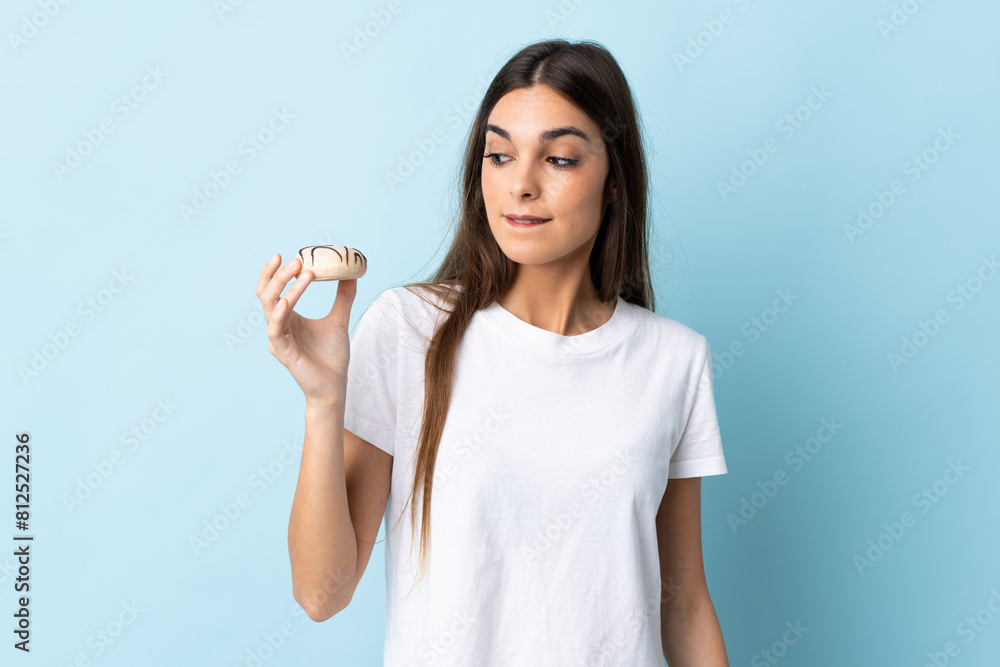 Young caucasian woman isolated on blue background holding a donut Young caucasian woman isolated on blue background holding a donut