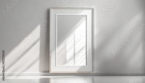 A minimalist picture frame casts geometric shadows on a white wall. Simplicity and design  with the interplay of light creating a dynamic space.