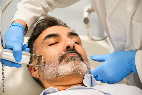 A man is getting a laser skin resurfacing treatment by a aesthetic doctor in a clinic.