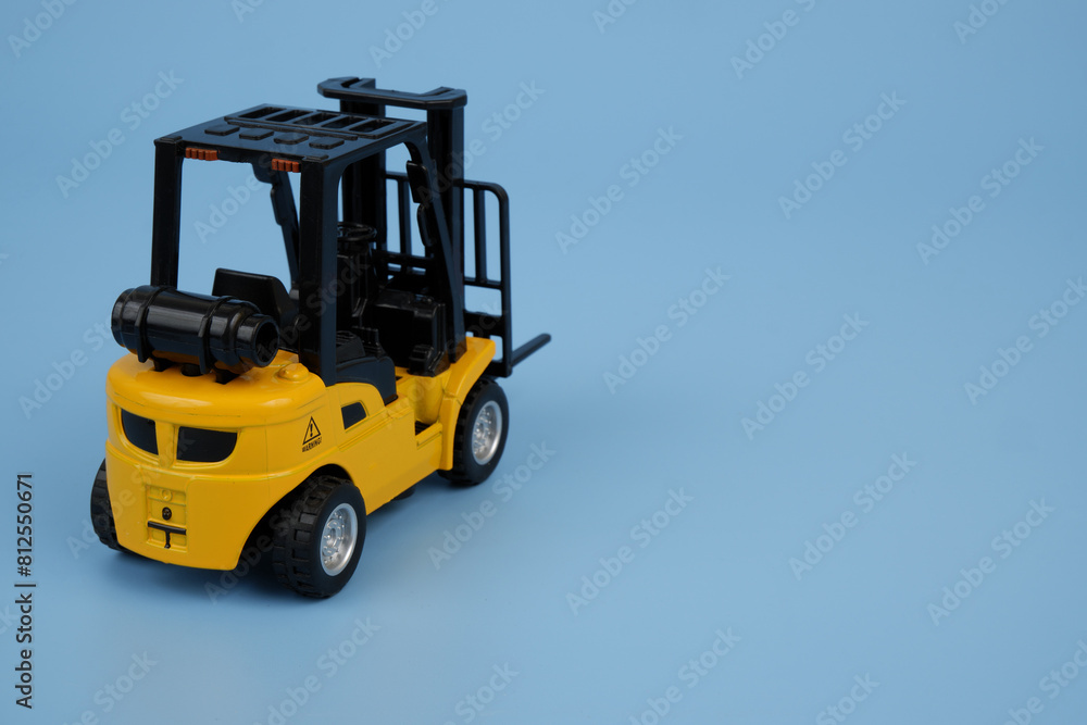 Yellow forklift model on blue background, copy space for text.