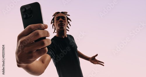 Young man taking a selfie with his smartphone in a studio