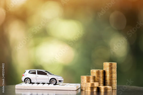 Car model put on the calculator and stacked gold coin with growing interest in the public park, Saving money for buy a new chattel or loan business investment in the future concept.