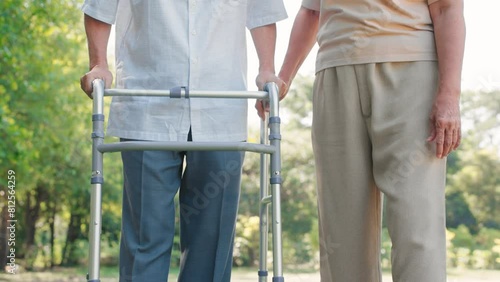Asian senior woman support and help husband walking with walker cane in the garden, Physical therapy concept