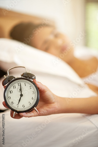 Woman, hand and alarm with zoom, sleeping and tired or lazy in morning with snooze and person in house. Bedroom, watch and wake up time after sleep, rest and relax with burnout, apartment or home