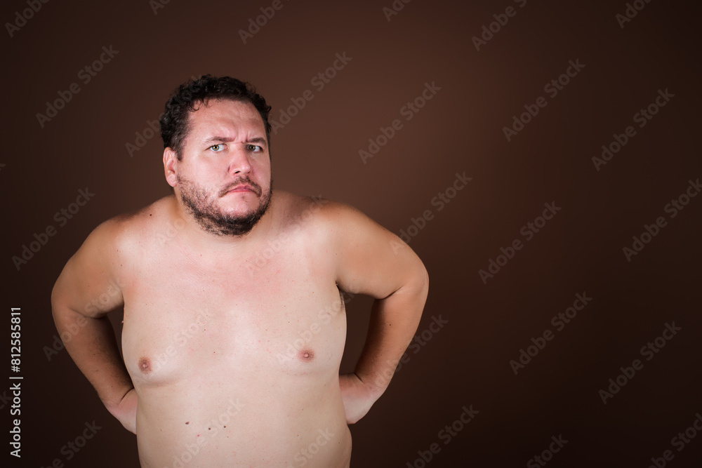 Anger and aggression. Upset fat man posing on a brown background. Anger and aggression. Upset fat man posing on a brown background.