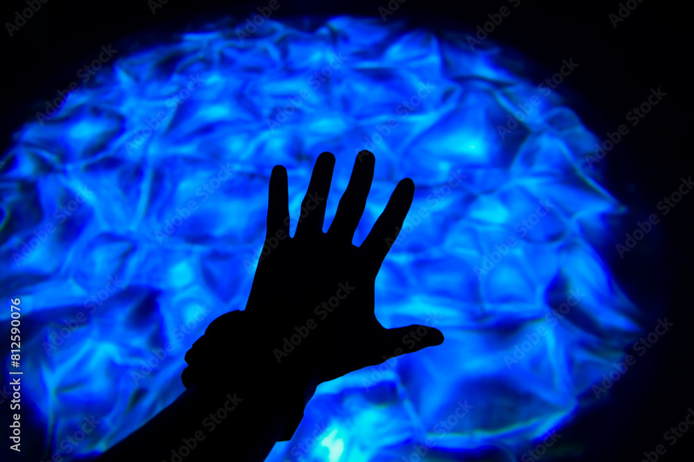 Hand shadow over blue contrast neo light, hand with light beautiful patterns represents having power,Colorful lights at night, Artistic photography,blue color light,abstract background. Hand shadow over blue contrast neo light, hand with light beautiful patterns represents having power,Colorful lights at night, Artistic photography,blue color light,abstract background.
