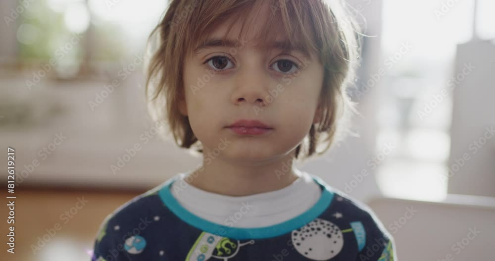 A cheerful young child stands indoors wearing a space-themed pajama set, smiling broadly in a well-lit room suggesting a relaxed, happy morning.
