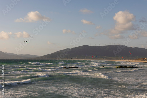 Many people kite surfing at sunset at Tarifa beach on a bright sunny day