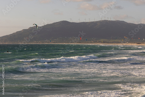 Group of many kite surfers surfing waves on the Atlantic ocean in Tarifa beach on a bright sunny day