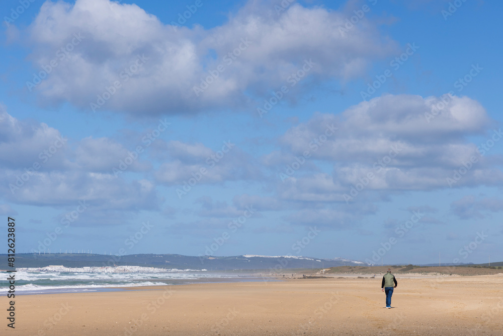 Tourists walking on the beach at Zahara de los Atunes  in Spain on a brigh sunny day at the seaside with blue sky
