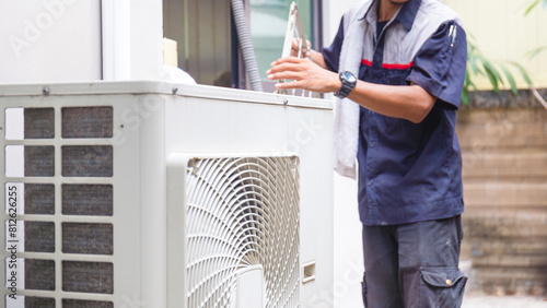 Selective focus of Air conditioner compressor with blurred technician man cleaning air conditioner in background, Repairman washing dirty compartments air conditioner