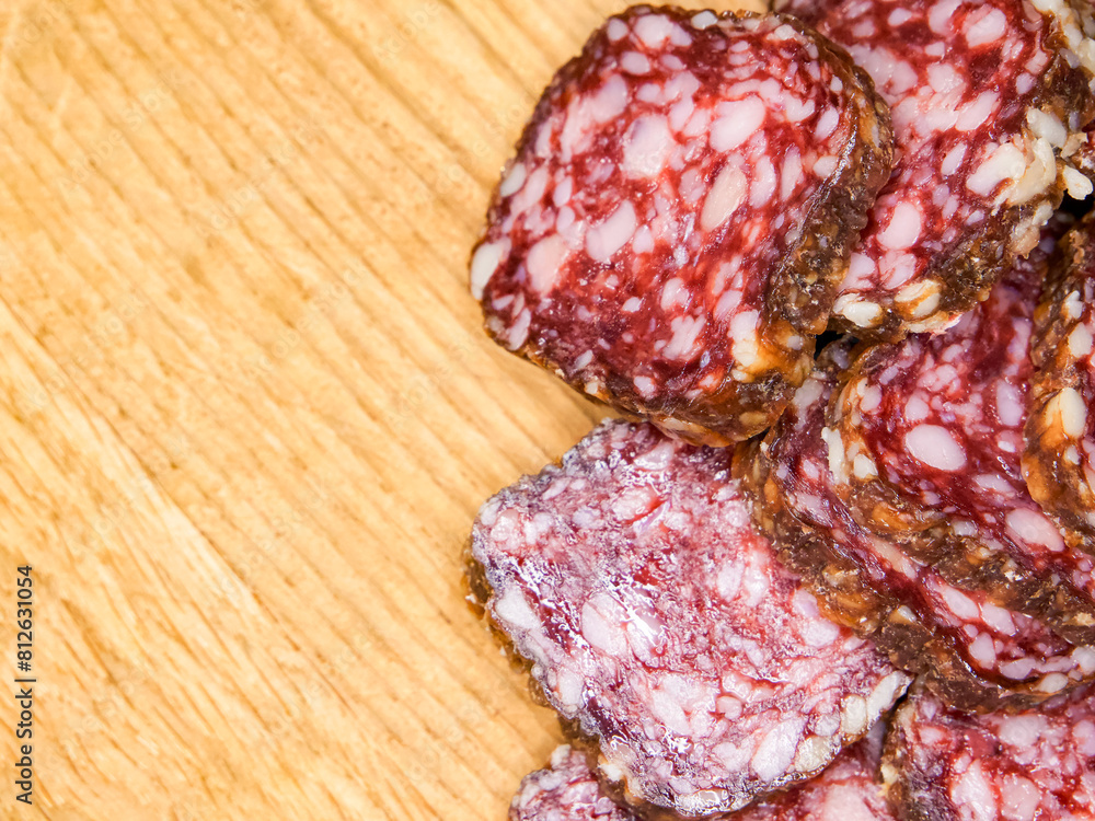 A close up of a wooden table with a pile of meat on it. The meat is sliced and he is salami. A close up of a wooden table with a pile of meat on it. The meat is sliced and he is salami.