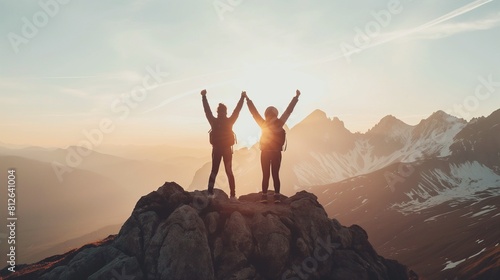 Three people raise their hands in the air  overcome obstacles together  and celebrate success and accomplishments at the top of a mountain.