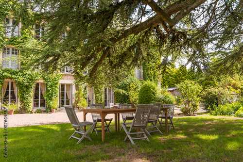 Outdoor lounge corner with wooden table and chairs surrounded by vegetation in Loire Valley in France