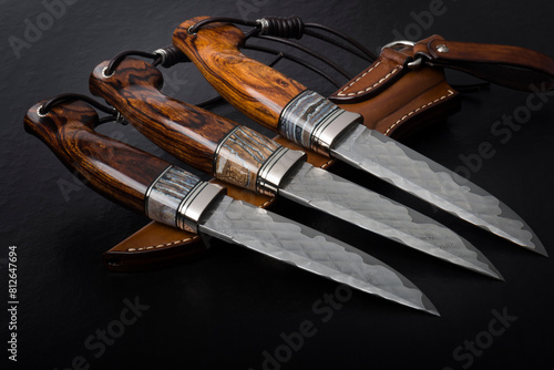 Three handmade hunting knives on a black background.