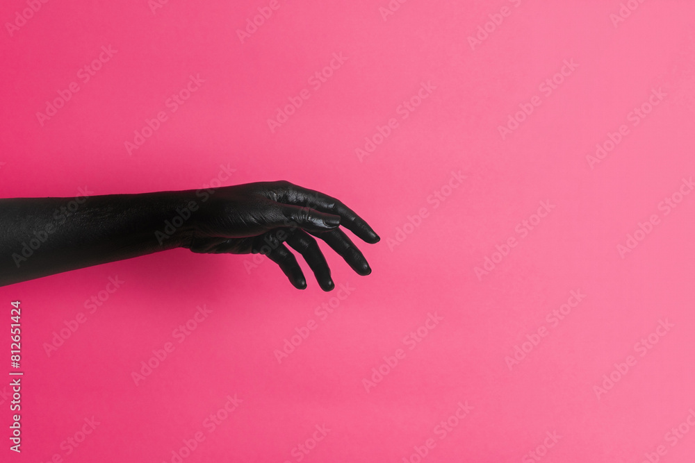 Fototapeta premium Black painted elegant woman's hand on her skin gesticulates on pink background. High Fashion art concept