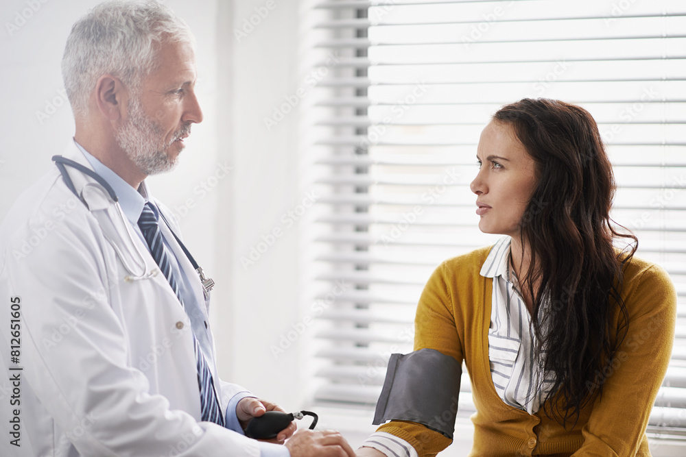 Obraz premium Doctor, blood pressure and woman talking at hospital with medical consultation for health insurance. Healthcare, stethoscope and check pulse for medical exam, wellness and hypertension diagnosis