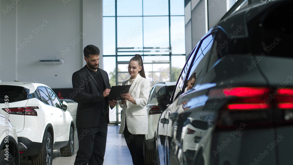 The buyer, a client of a modern car dealership, chooses a car. A dealer talks about a new model of a modern electric car. The concept of test drive, buying an electric car or renting it. The buyer, a client of a modern car dealership, chooses a car. A dealer talks about a new model of a modern electric car. The concept of test drive, buying an electric car or renting it.