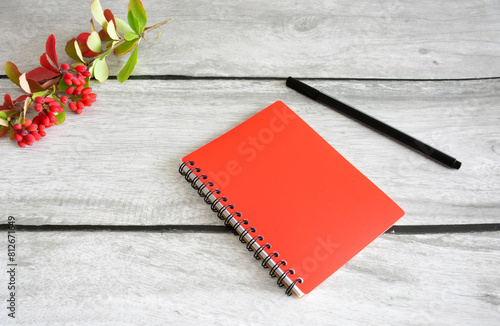 a red notebook with a pen on a wooden table flat lay