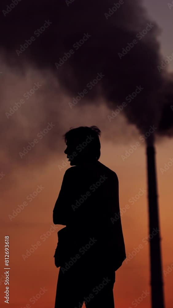 Silhouette of a man on the polluted air background. Evening sky with dark smoke going from industrial pipes and a man outdoors. Environmental pollution. Vertical video Silhouette of a man on the polluted air background. Evening sky with dark smoke going from industrial pipes and a man outdoors. Environmental pollution. Vertical video