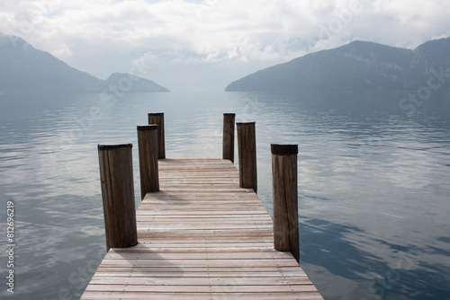Wooden pier on the lake. Calm, peaceful landscape. The beauty of nature in Europe. Quiet water, fog, mountains and sky. Scenic view