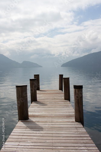 Wooden pier on the lake. Calm, peaceful landscape. The beauty of nature in Europe. Quiet water, fog, mountains and sky. Scenic view