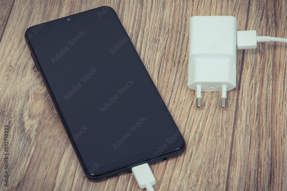 Black smartphone and charger using to charge empty battery. Various devices charging concept Black smartphone and charger using to charge empty battery. Various devices charging concept