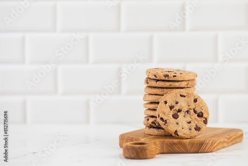 Stacked chocolate chip cookies on a wooden board