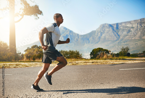 Running, man and fitness for outdoor training, cardio workout or endurance challenge. Lens flare, wellness and male athlete person in road for morning exercise, marathon or performance in California
