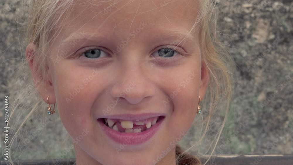 Close-up of the face of an upset blonde girl. She is smiling, and it is apparent that she is missing a tooth Close-up of the face of an upset blonde girl. She is smiling, and it is apparent that she is missing a tooth