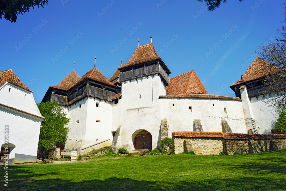 Exterior view of a fortified church in the village of Viscri, Romania. Medieval landmark of Transylvania: fortress with defensive walls, numerous towers and a church in a Romanian village.