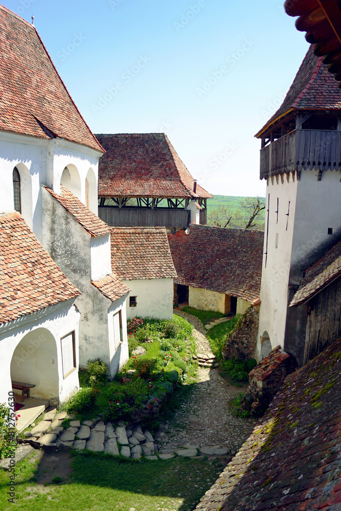 The courtyard of a fortified church in the Romanian village of Viscri. A fragment of a church, defensive walls and towers - the architecture of a famous Transylvanian landmark. The courtyard of a fortified church in the Romanian village of Viscri. A fragment of a church, defensive walls and towers - the architecture of a famous Transylvanian landmark.