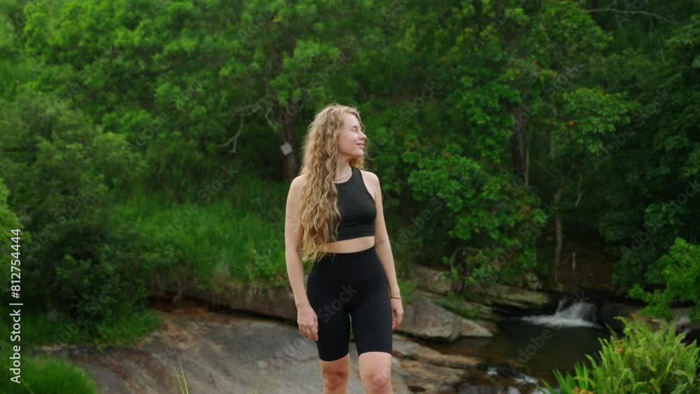 Active young woman hikes in mountain terrain by rocky river. Curly-haired hiker explores, enjoys serene nature alone. Healthy lifestyle, adventure travel in lush green outdoor setting, daytime hike. Active young woman hikes in mountain terrain by rocky river. Curly-haired hiker explores, enjoys serene nature alone. Healthy lifestyle, adventure travel in lush green outdoor setting, daytime hike.