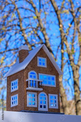 Close-up of a neat brown house with light blue light in the windows on a semi-blurred background of trees and sky © andreyfire