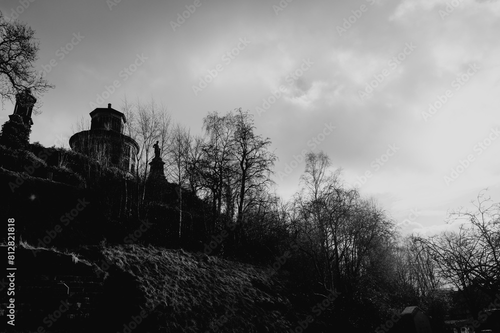 Obraz premium Glasgow Scotland: 12th Feb 2024: Glasgow Necropolis on sunny winter day with spooky bare trees. Black and white white