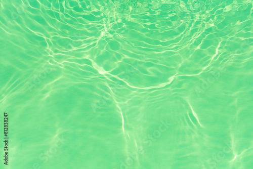 Blue water with ripples on the surface. Defocus blurred transparent blue colored clear calm water surface texture with splashes and bubbles. Water waves with shining pattern texture background.