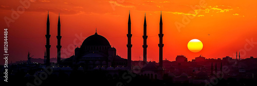 sunset mosque tower silhouetted against the orange sky, with a white cloud in the foreground