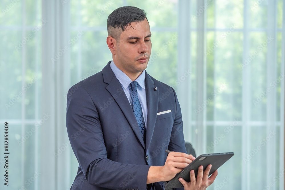 Fototapeta premium A man in a suit is using a tablet.
