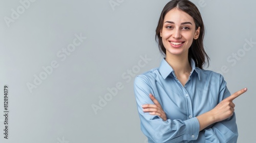 Happy young smiling professional business woman wearing blue shirt looking at camera pointing finger away at copy space showing aside presenting advertising offer standing isolated at gray background  photo