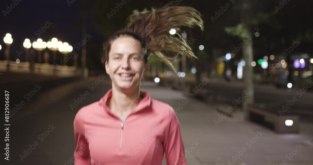 Beautiful woman in a pink jacket and sports attire running in a city setting during the evening. Sport activities at night. Portrait recorded at 120 fps. Beautiful woman in a pink jacket and sports attire running in a city setting during the evening. Sport activities at night. Portrait recorded at 120 fps.